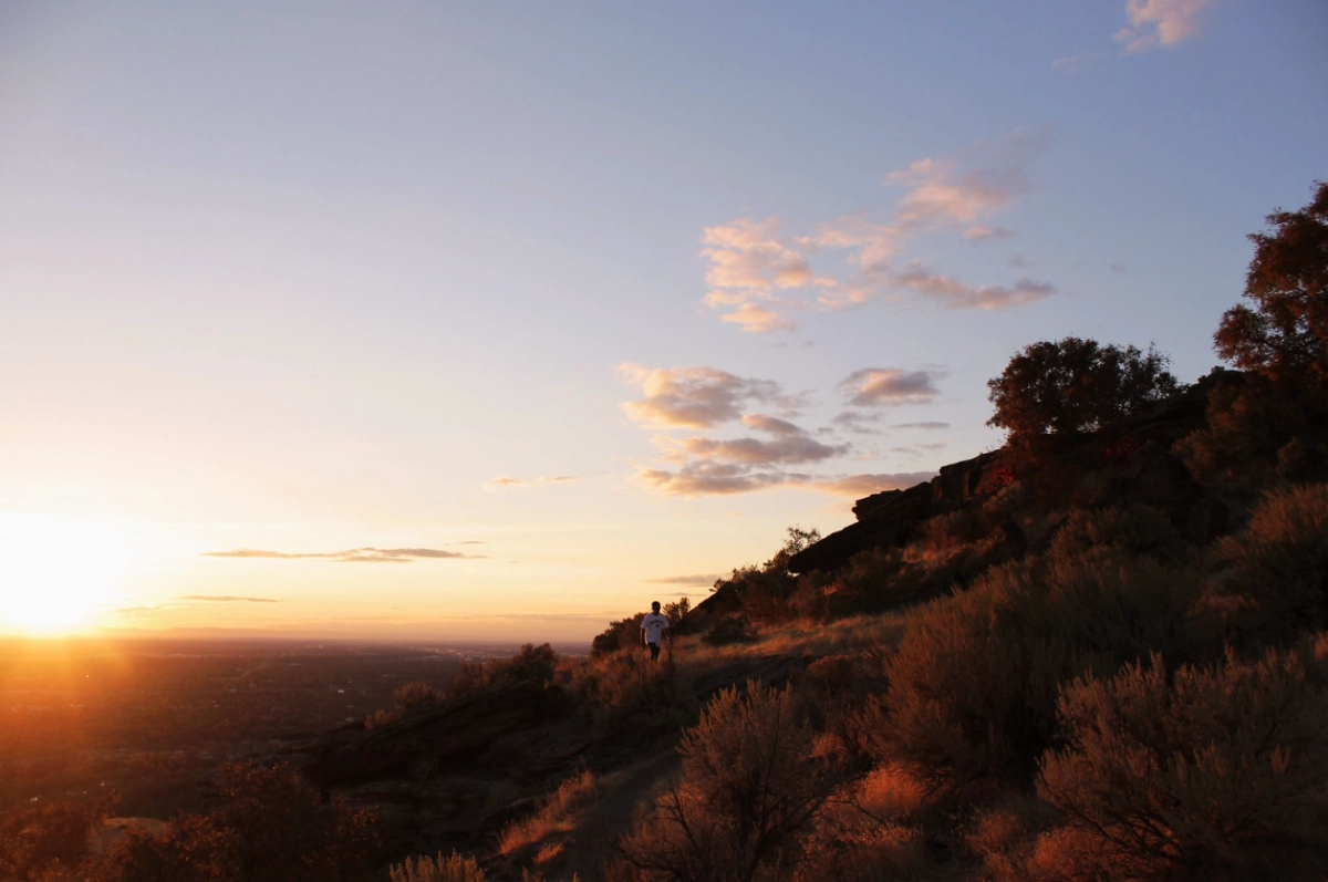 A person climbing the hillside at Table Rock above Boise near sunset.