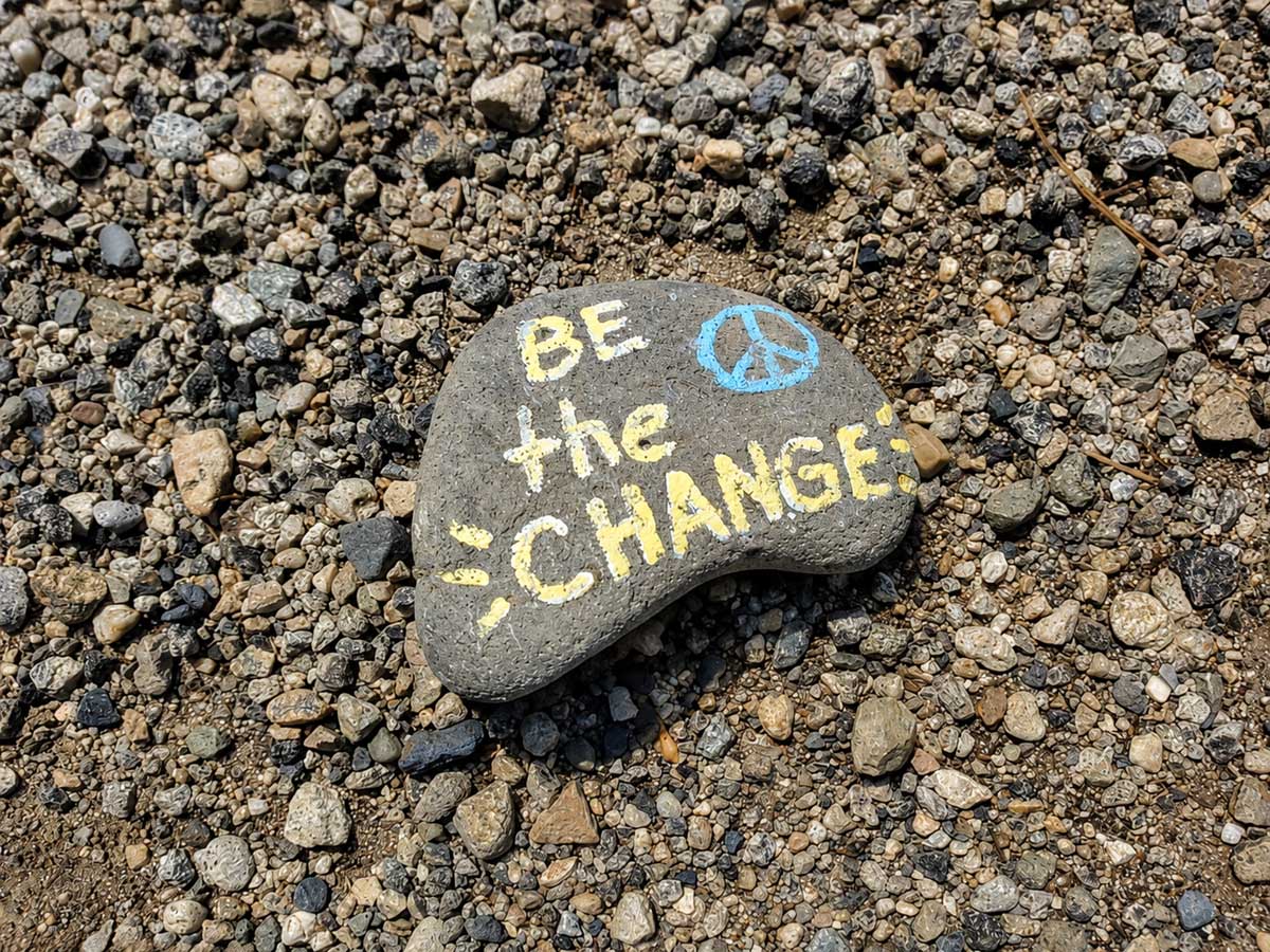 Painted river stone with the words “Be the Change” left beside a Boise trail as a small public message of encouragement.