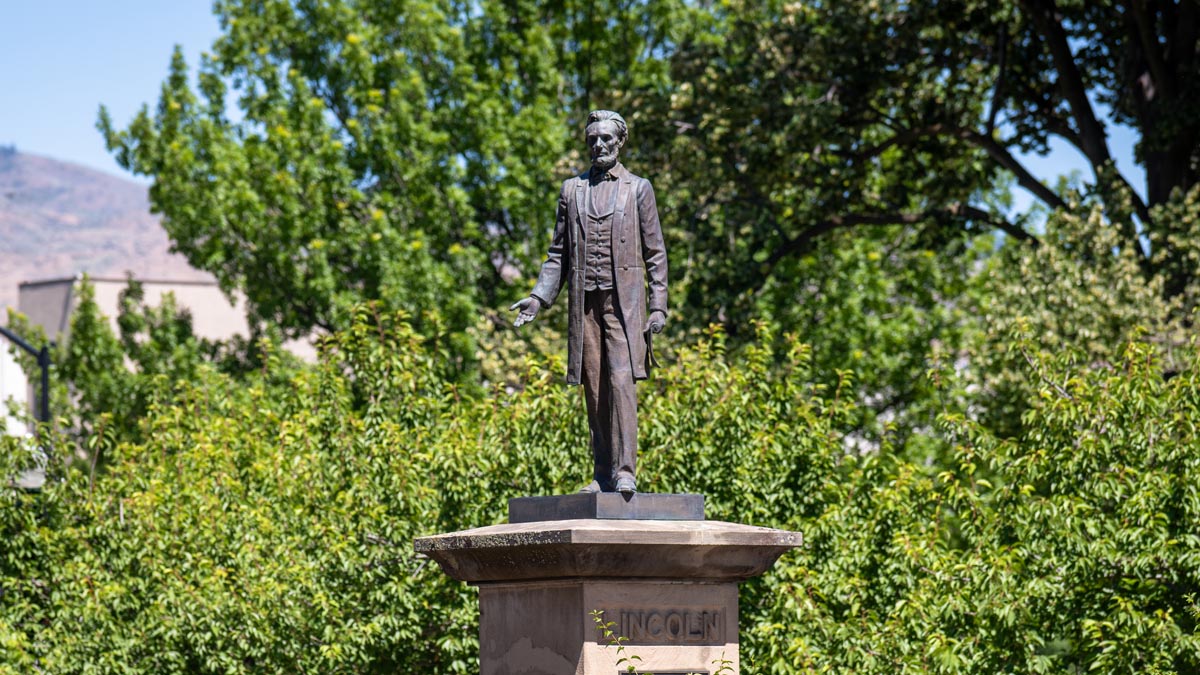 Abraham Lincoln statue on the Capitol Mall in downtown Boise, surrounded by trees and foothills.