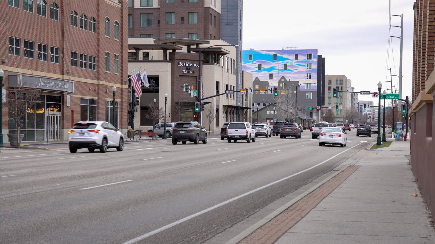 Downtown Boise street scene with wide traffic lanes, sidewalks, signals, and brick buildings near 8th Street.