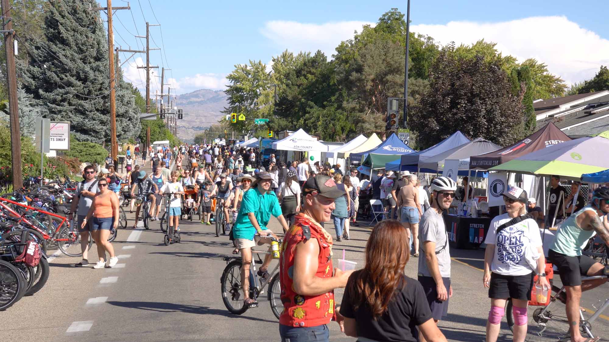 People walking and cycling among neighborhood booths at Boise’s Open Streets event