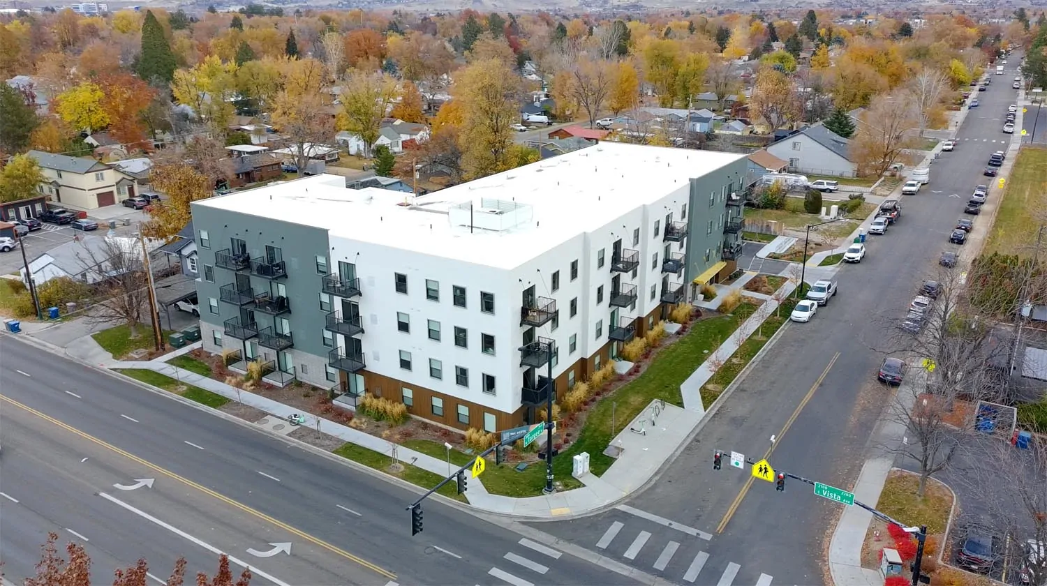 A recently built apartment building along Vista Avenue in Boise, showing a multi-story block design with units stacked above and beside one another, set close to a busy arterial road.